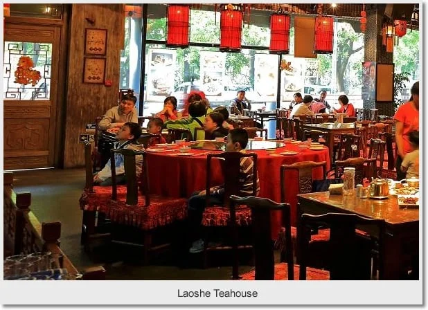 Wooden tables and chairs beneath red lanterns inside Lao She Teahouse
