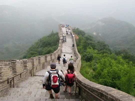 Visitors walking along Badaling Great Wall in misty green hills
