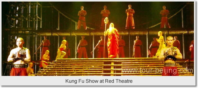 Martial-arts stage performers in orange robes on a stepped theatre set