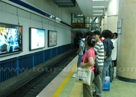 Passengers waiting behind the marked line on a Beijing metro platform